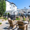 a patio with seating and trees with a building behind
