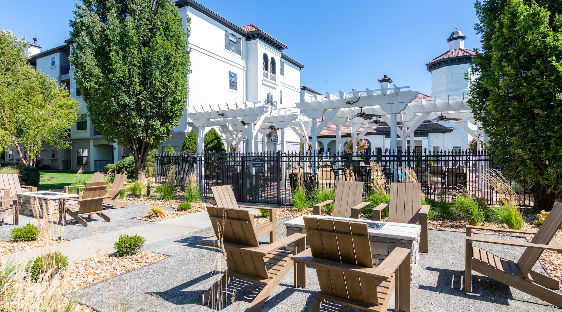 a patio with seating and trees with a building behind
